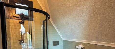 A modern bathroom with a glass shower enclosure, a white toilet, and a wooden vanity with a large bowl sink.