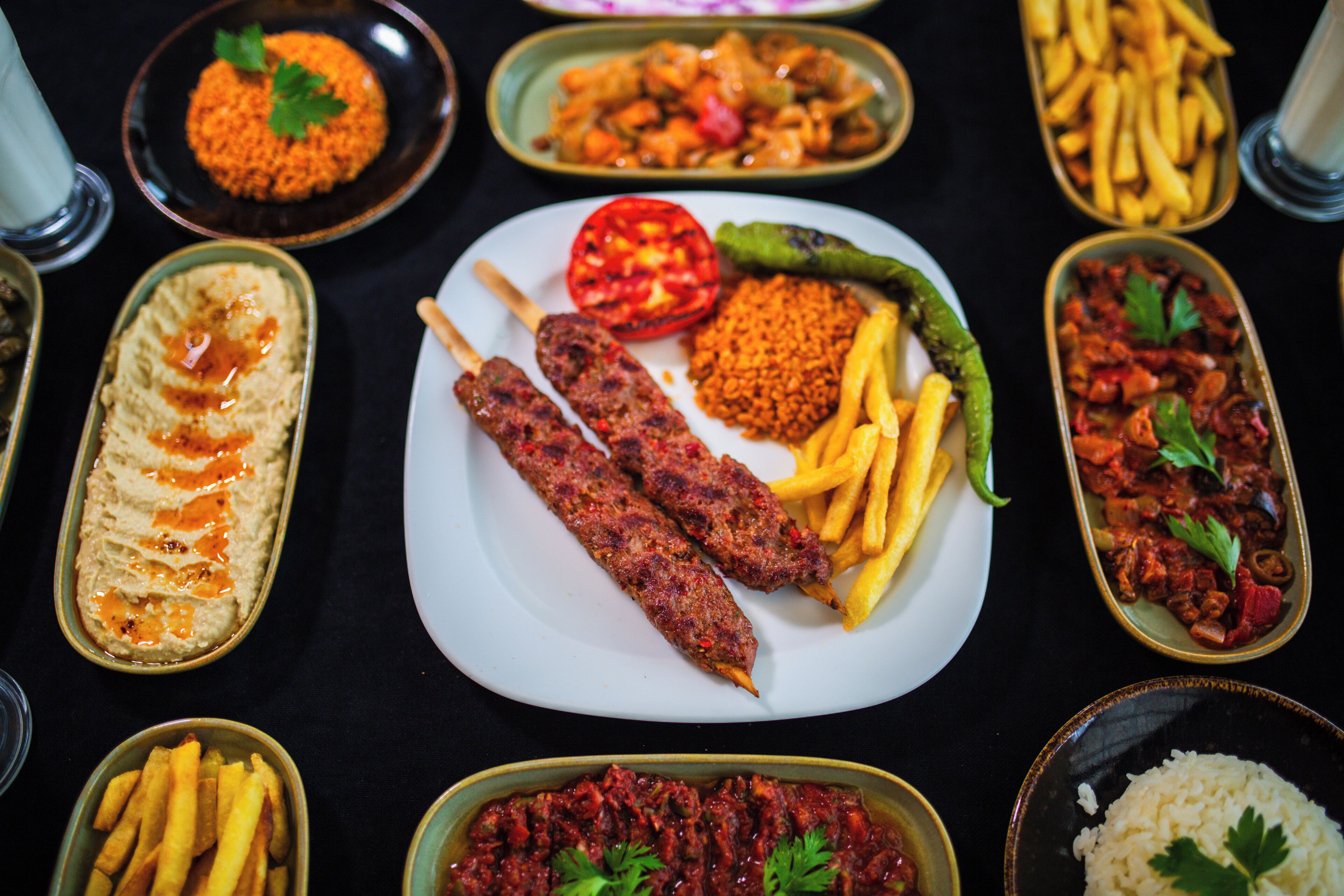 A variety of dishes including kebabs, fries, hummus, and rice.