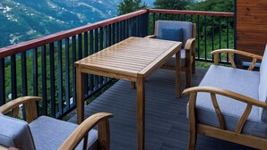 Una terraza de madera con una mesa y sillas con vistas a un paisaje montañoso.