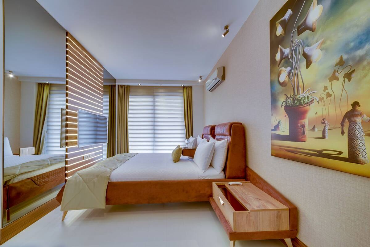 Ein modernes Hotelzimmer mit einem großen Bett, einem Nachttisch aus Holz, einem Spiegel und einem Bild an der Wand.