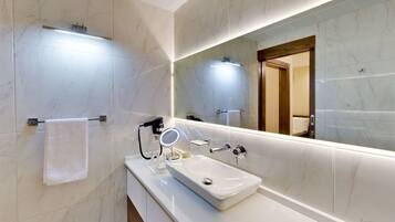Un baño moderno con un lavabo de mármol blanco, un espejo grande y un perchero para toallas.