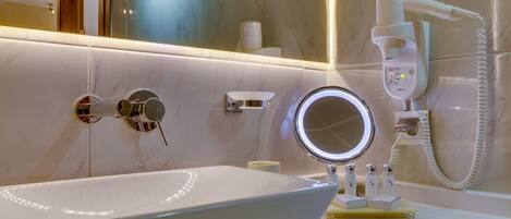 Un baño moderno con un espejo grande, un secador de pelo de mano y un lavabo con encimera de mármol.