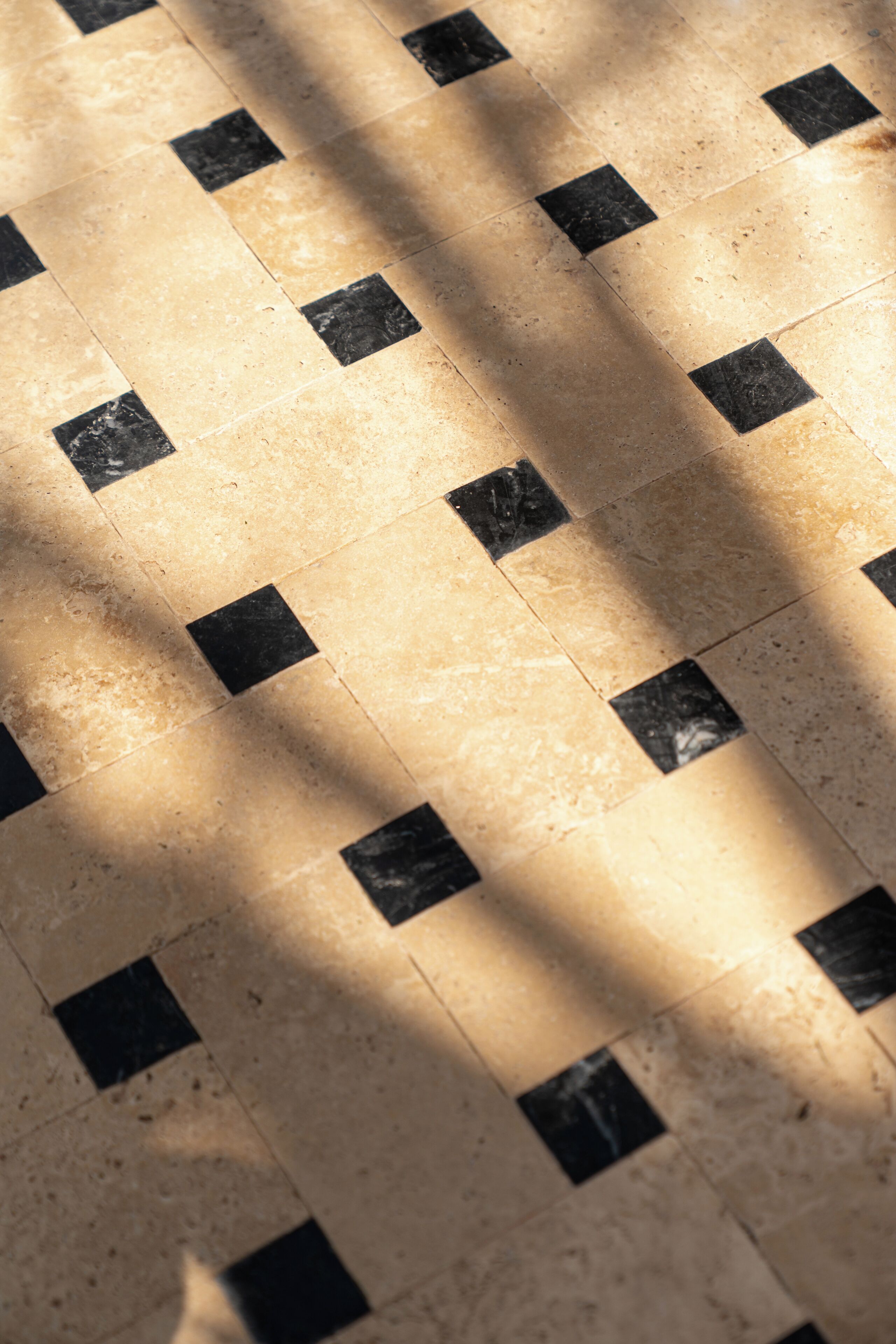 A floor with a checkered pattern of beige and black tiles.