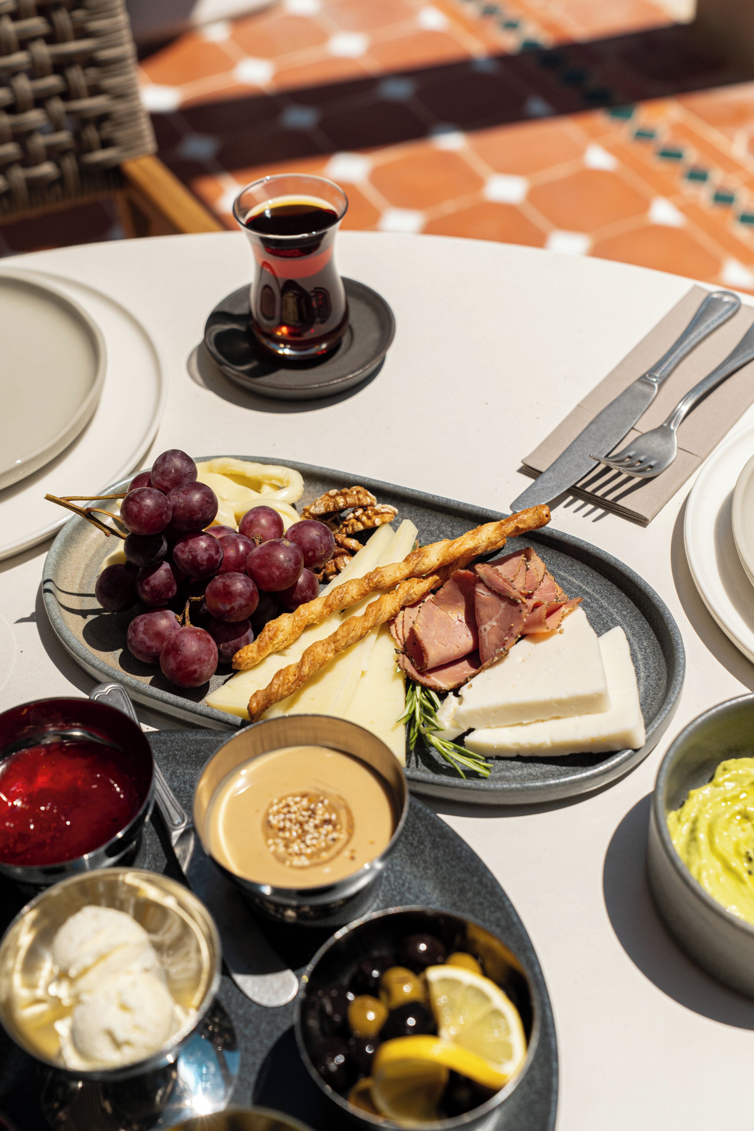 A table set with a variety of food items including grapes, cheese, nuts, and a small cup of coffee.