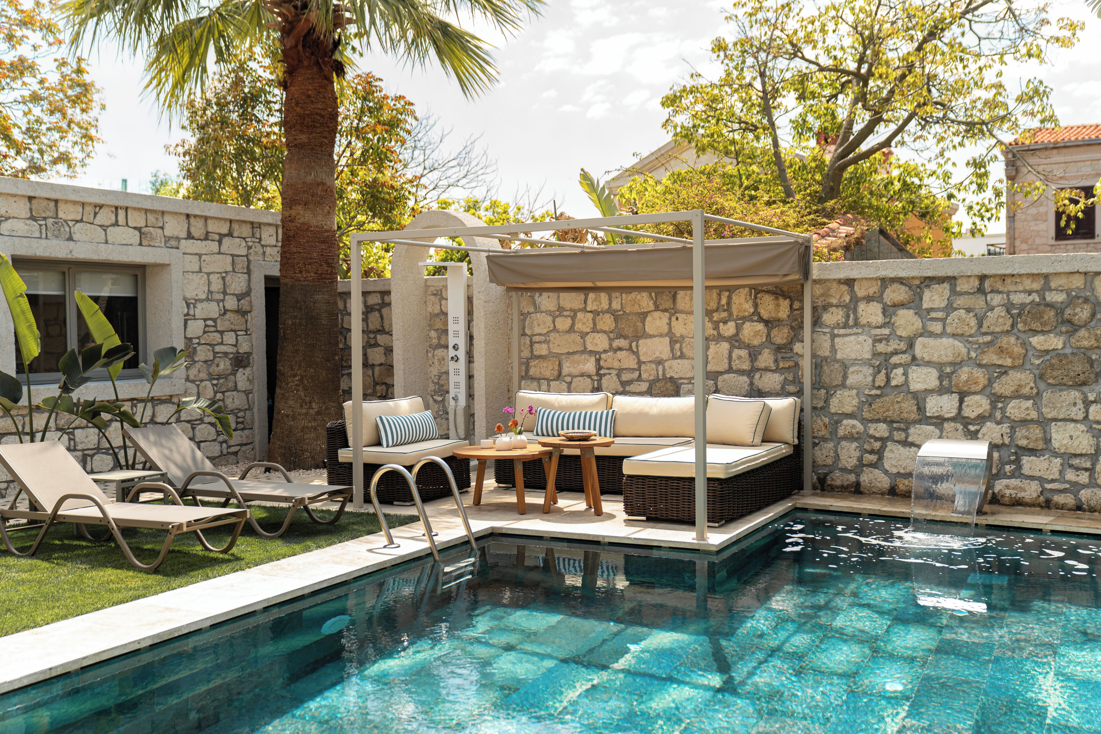A swimming pool with lounge chairs and a covered seating area.