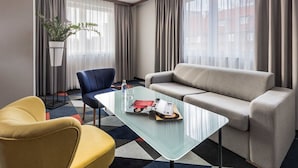 A hotel room with a sofa, armchair, and a glass coffee table with a magazine. - Vulcan Hotel (Szczecin)
