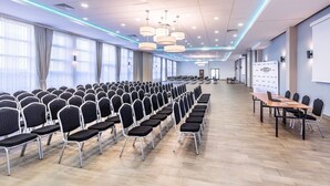 A conference room with rows of chairs, a long table, and a presentation screen. - Vulcan Hotel (Szczecin)