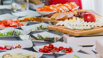 Una mesa de buffet con diversos alimentos, incluyendo queso, frutas y verduras.