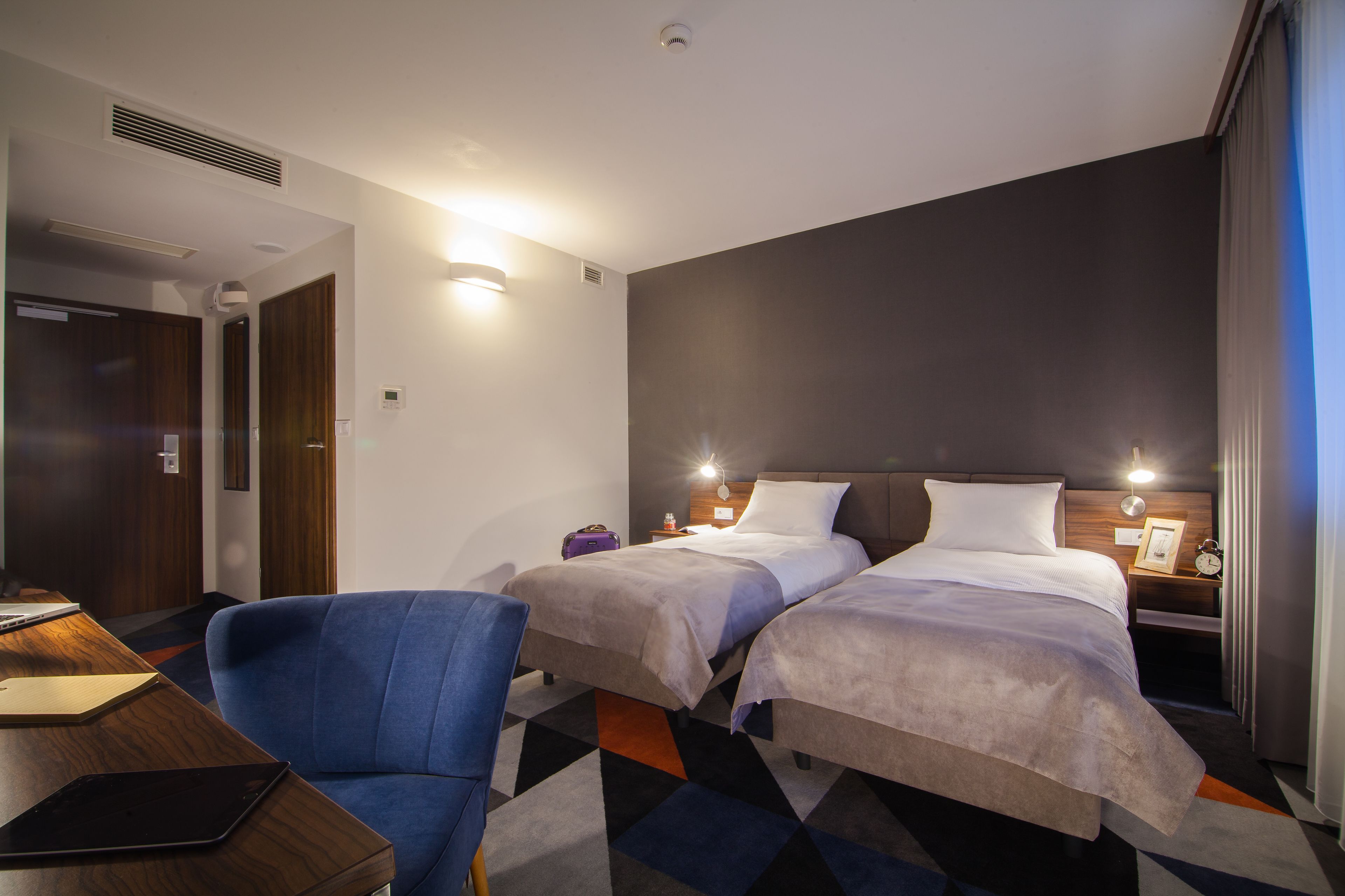 Habitación de hotel con dos camas, un escritorio y una silla.