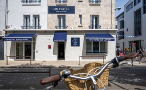 A hotel named "UN HOTEL SUR LE PORT" with a sign above the entrance, a visible fire alarm, and a bicycle in the foreground. - Un Hôtel sur le Port (La Rochelle)