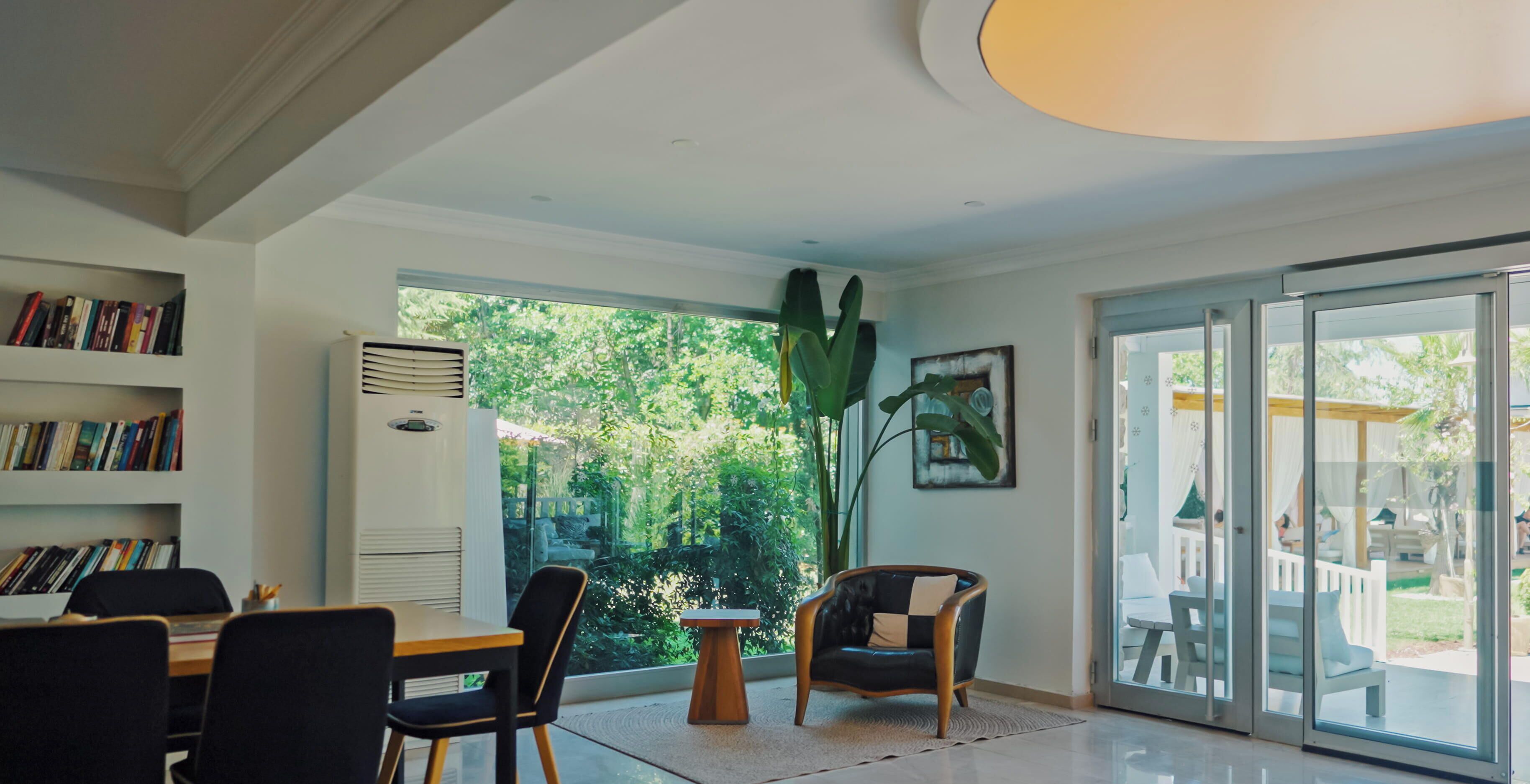 Una habitación con una mesa de comedor, sillas, una estantería, un ventanal grande y un cerramiento de vidrio corredizo que da a un área exterior.