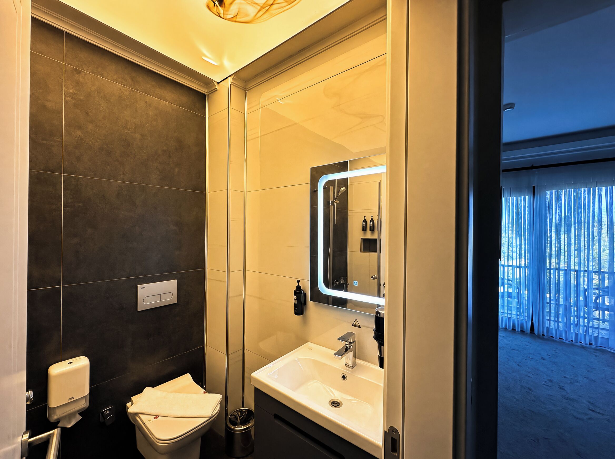 Un baño moderno con inodoro, lavamanos y espejo.