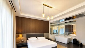 Una habitación de hotel moderna con una cama grande, una bañera integrada, un tocador con espejo y un candelabro en el techo.