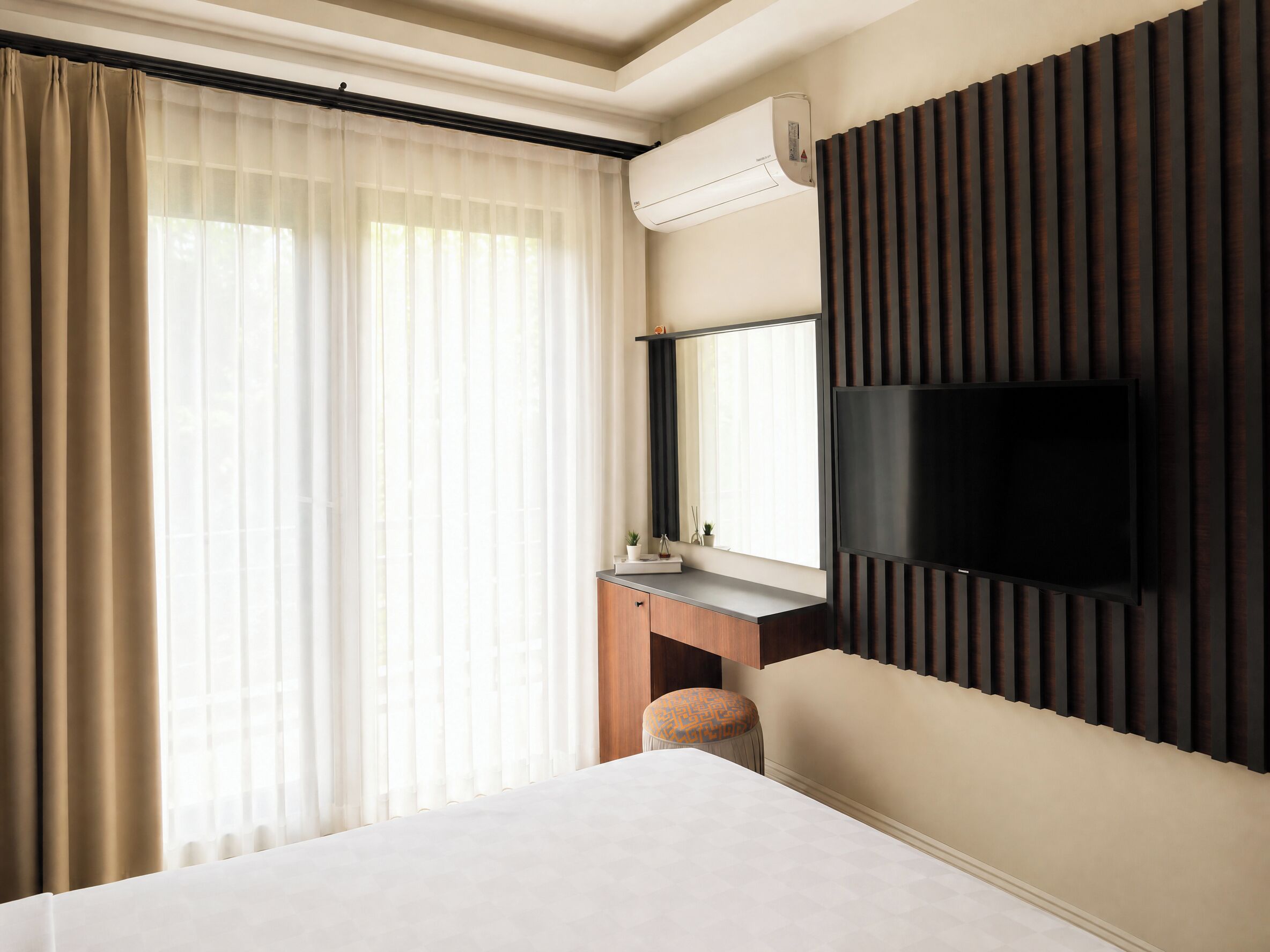 Une chambre d’hôtel équipée d’un lit, d’un bureau avec un miroir, d’un téléviseur à écran plat et d’un système de climatisation.