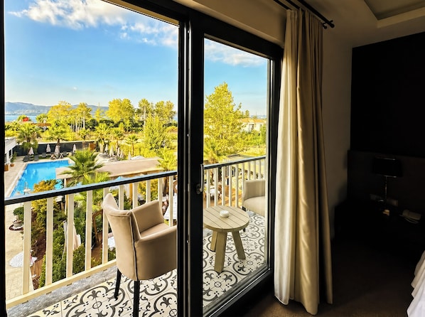 A balcony with a pool, outdoor furniture, and a view of a landscape with trees and a distant body of water. - Didi Hotel Sapanca (Sapanca)