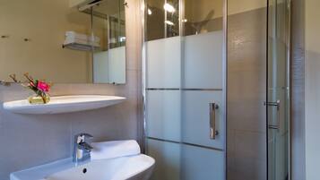A modern bathroom with a white sink, a mirror above it, and a glass shower enclosure.