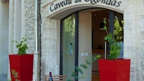 The exterior of Caveau du Vidouras, featuring a stone facade, a glass entrance, and red planters with greenery. - Hostellerie Le Beffroi (Vaison-la-Romaine)