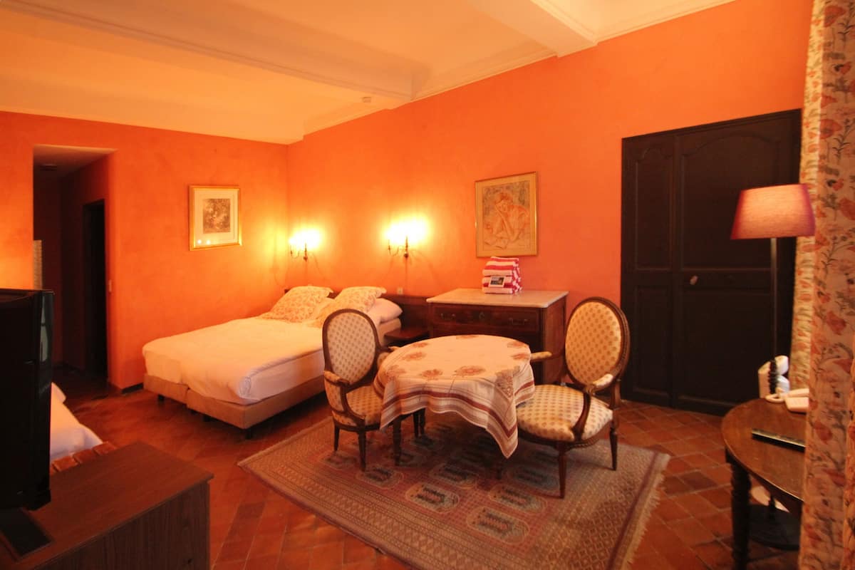 Une chambre avec deux lits, une petite table, deux chaises, un bureau et une lampe.