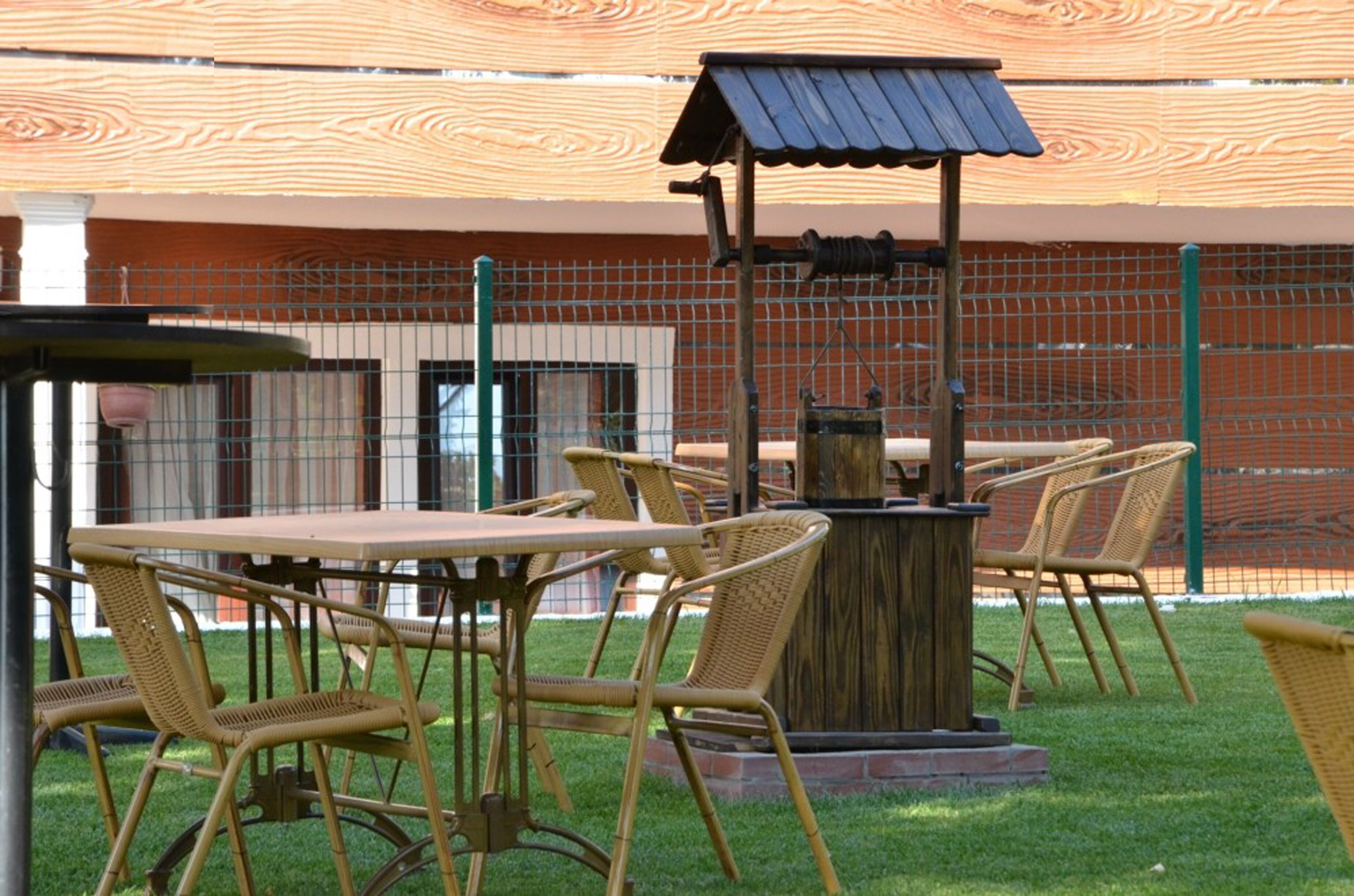 Un patio al aire libre con mobiliario de mimbre y una mesa de madera.