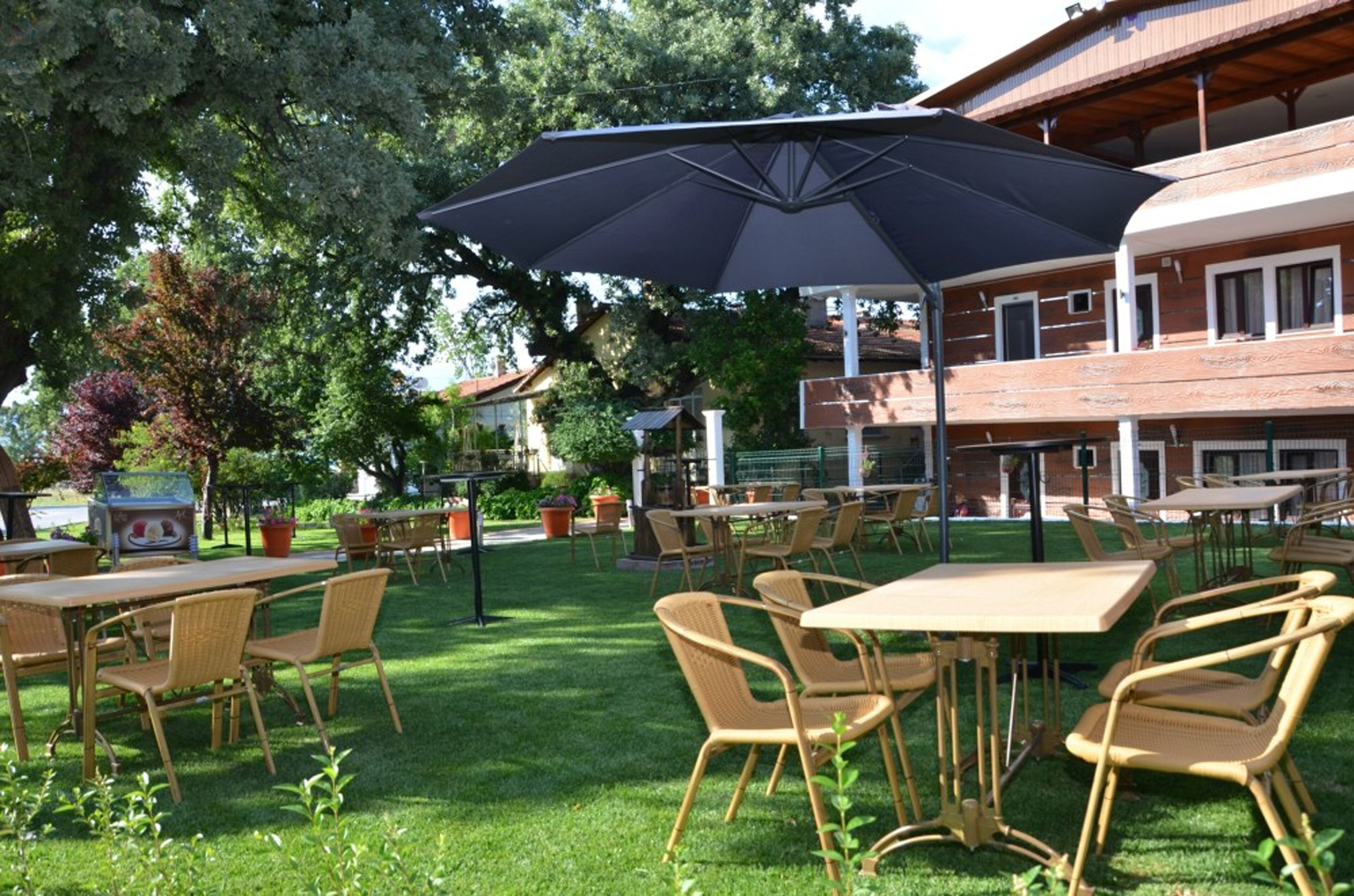 Un patio al aire libre con mesas y sillas, un paraguas grande y un edificio en el fondo.