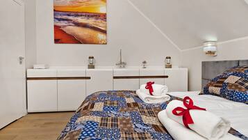 Un dormitorio moderno con una cama grande, vistas al atardecer, un aparador blanco y un pequeño modelo de barco.