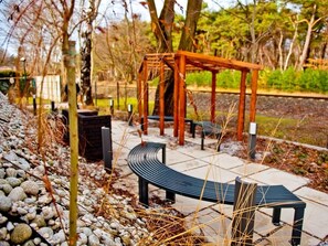 A park with a curved bench, a wooden pergola, and a stone pathway. - Willa Haven BlueApart Jastarnia (Jastarnia)