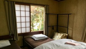A traditional Japanese-style room with tatami flooring, a low wooden bed frame, and a shoji screen window. - Guest House YAMASHITA-YA - Hostel (Nanto)