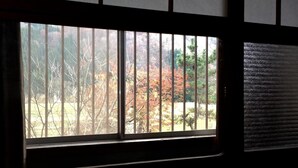 A window with a view of trees and a wooden structure outside. - Guest House YAMASHITA-YA - Hostel (Nanto)