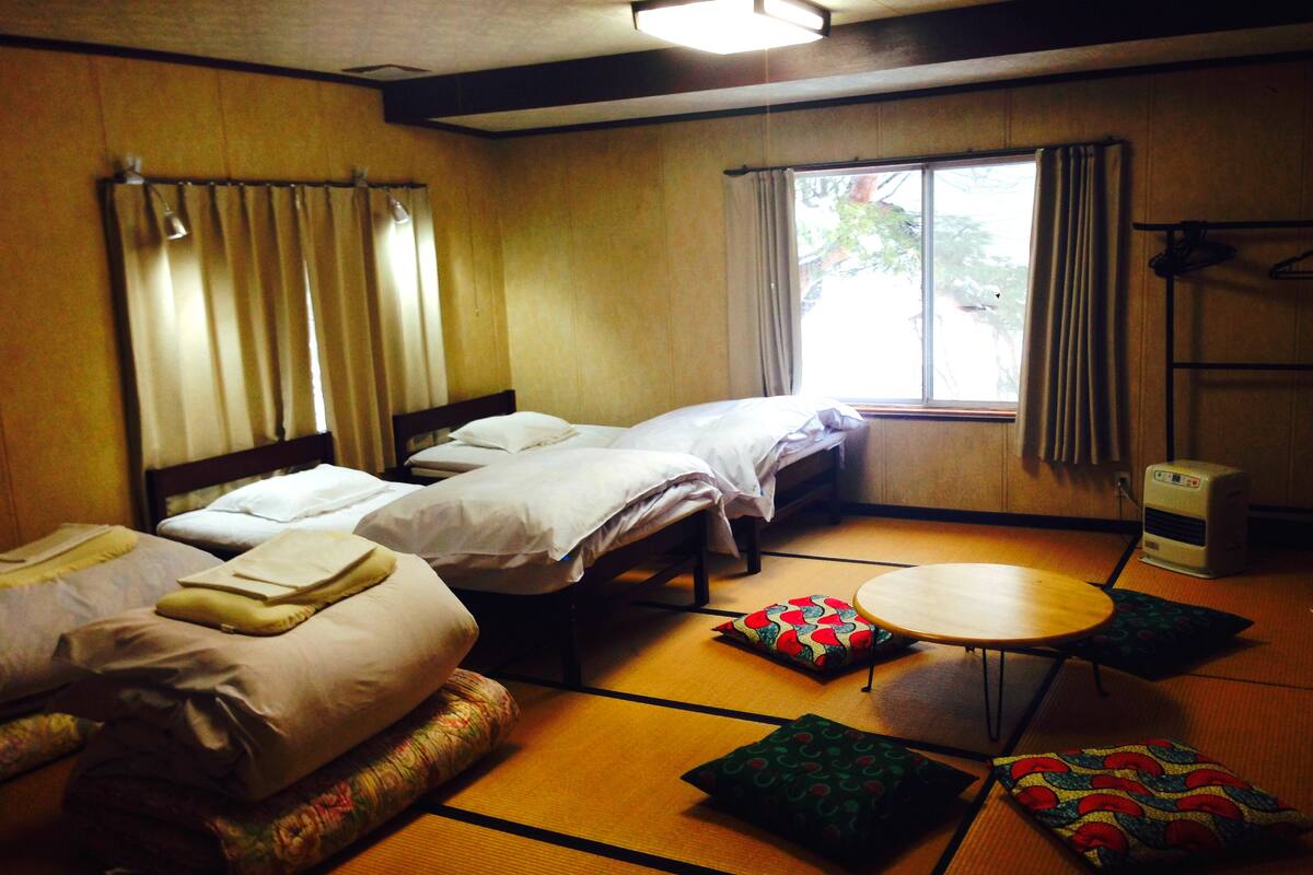 A hotel room with two beds, a small round table, and a heater.