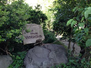 A stone sign with 'Yamashita-Ya' written on it, surrounded by greenery. - Guest House YAMASHITA-YA - Hostel (Nanto)