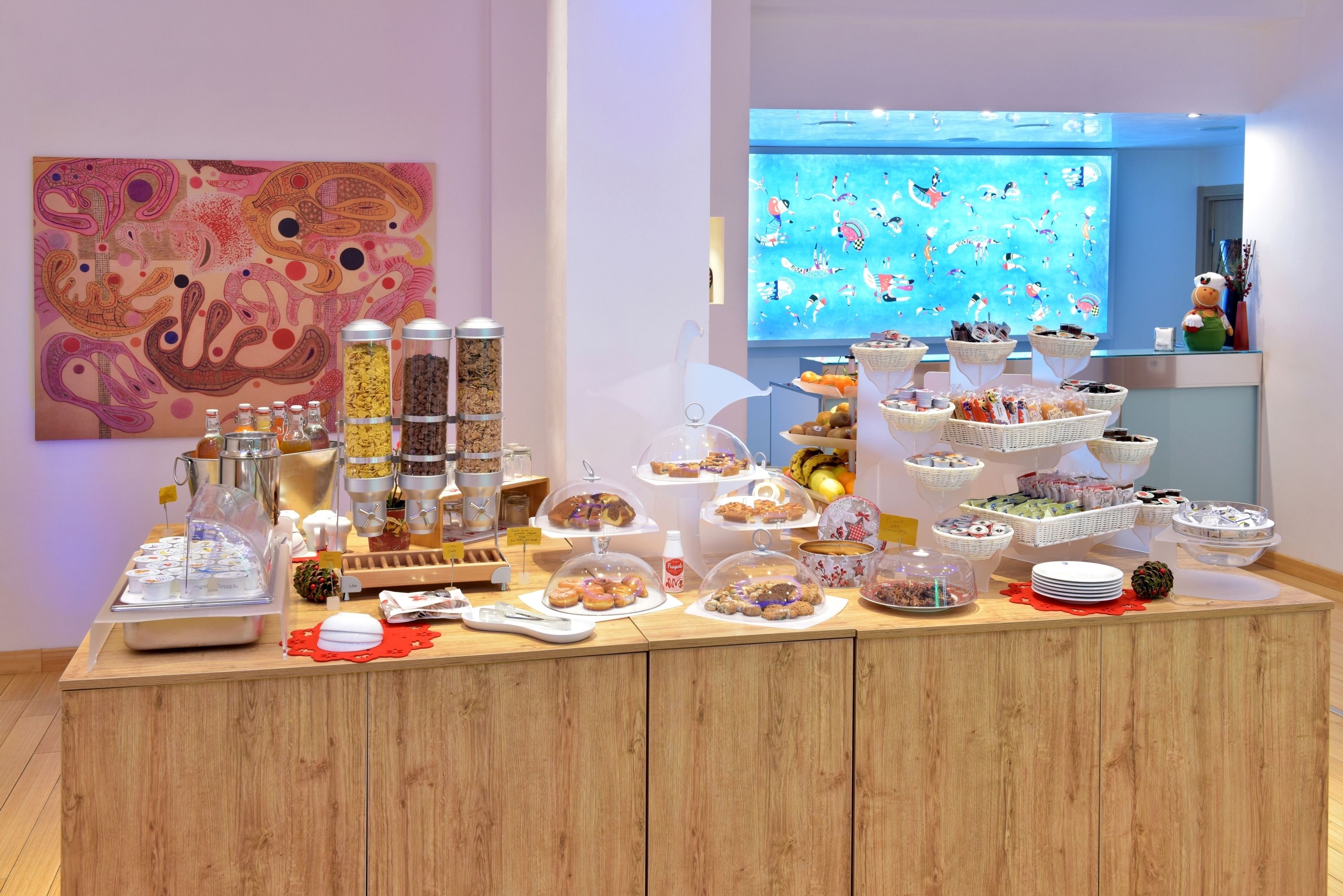 Un buffet proposant une variété de plats et, au mur, un tableau abstrait aux couleurs vives.