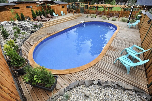 A wooden deck with a swimming pool, surrounded by potted plants and outdoor furniture. - APLEND Chaty Lux Tatry Holiday (Velky Slavkov)