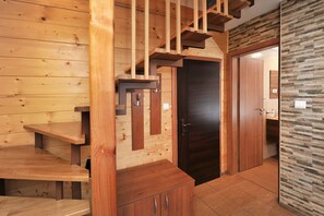 Una escalera de madera con una puerta oscura al final, que conduce a una habitación con pared de piedra.