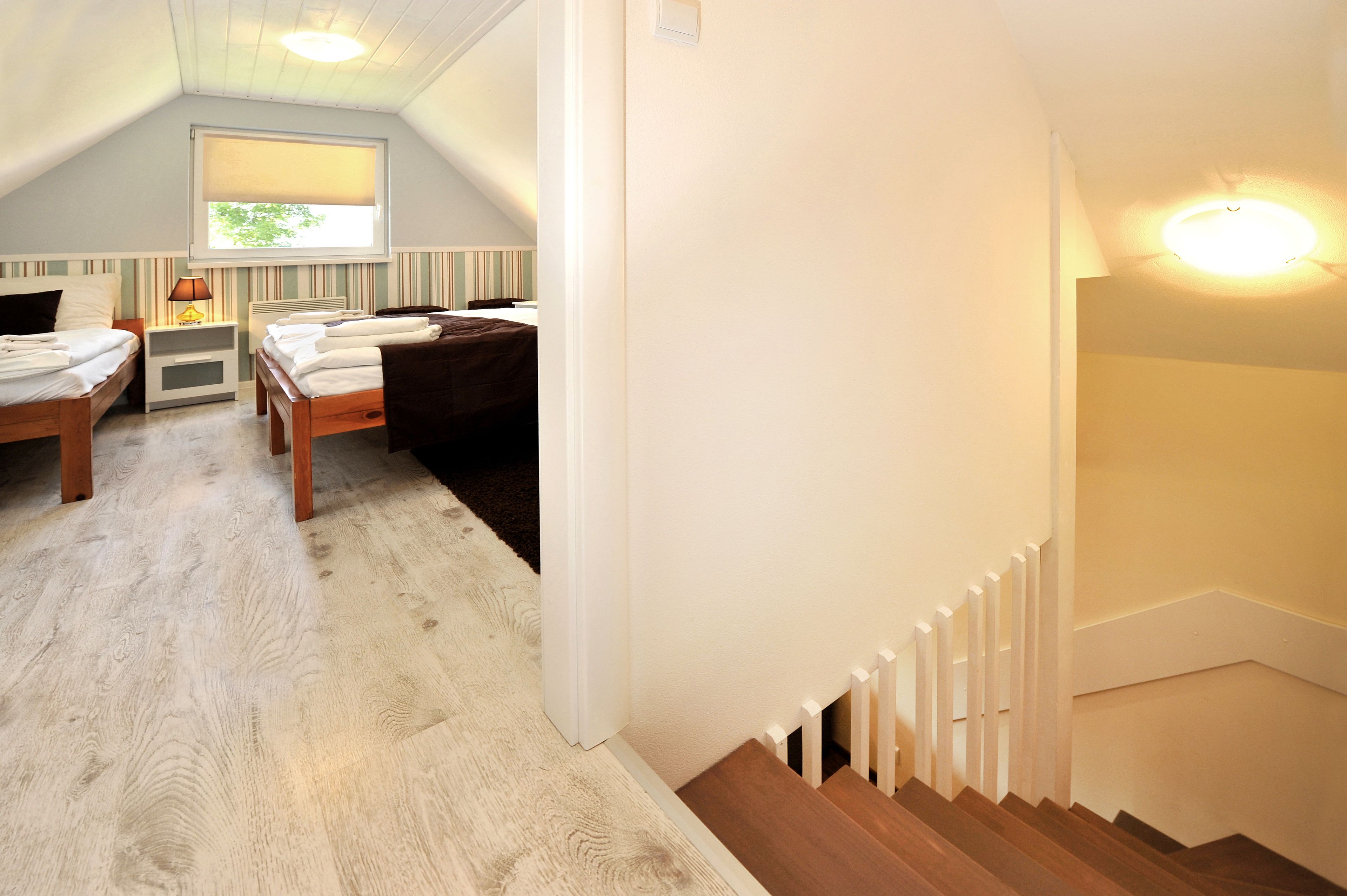 Une chambre confortable située sous les toits, avec deux lits, une fenêtre donnant sur un beau paysage et un escalier.