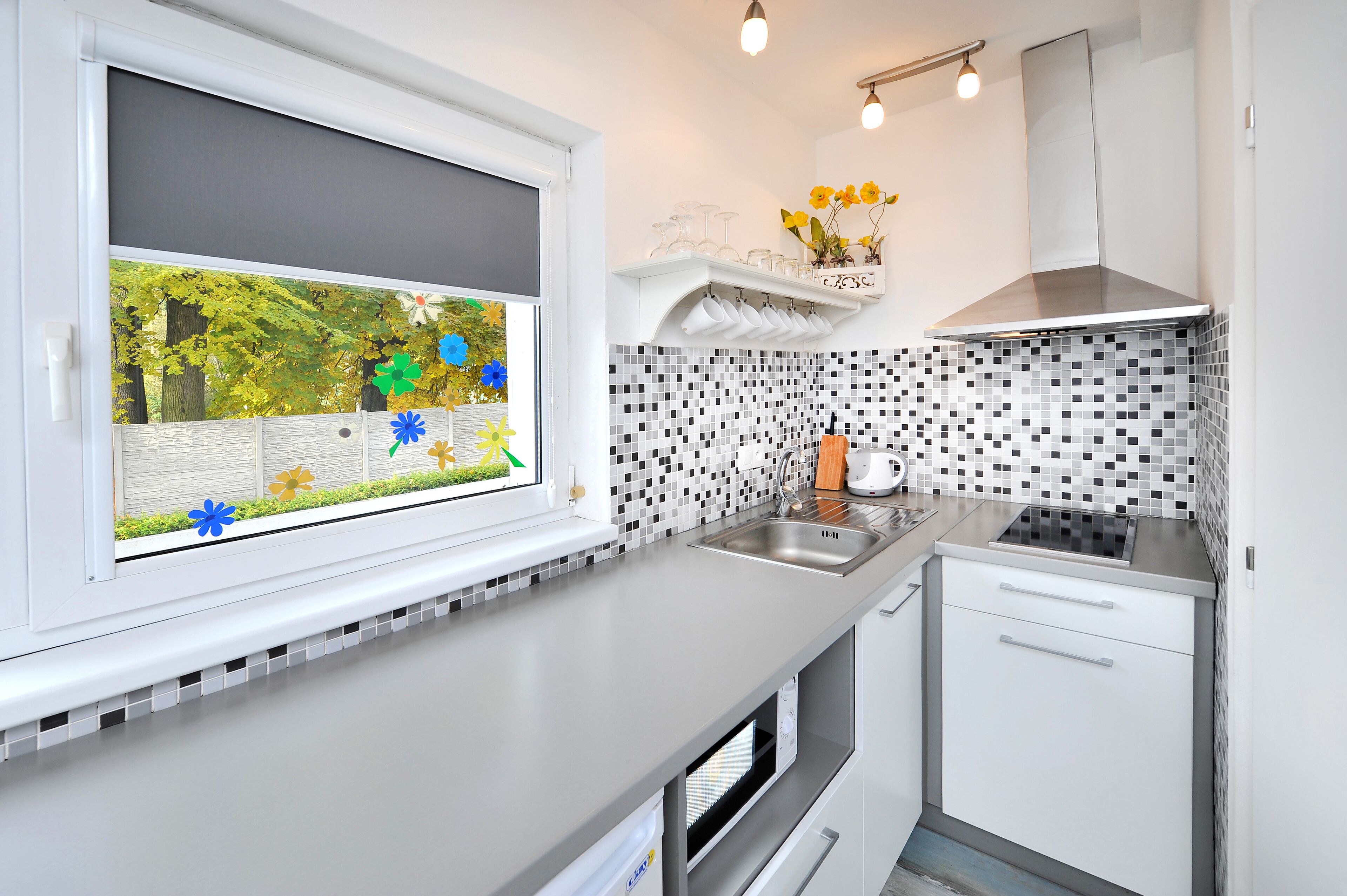 Une cuisine moderne avec une fenêtre, un évier, une cuisinière et un four à micro-ondes.