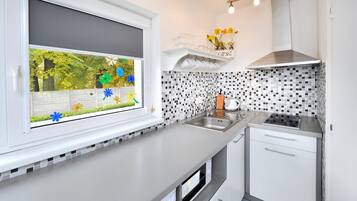 Une cuisine moderne avec une fenêtre, un évier, une cuisinière et un four à micro-ondes.
