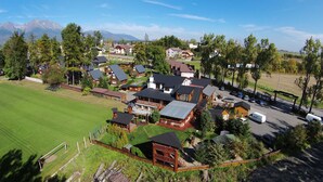 A residential area with houses, a green field, and mountains in the background. - APLEND Chaty Lux Tatry Holiday (Velky Slavkov)
