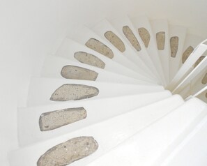 A spiral staircase with white steps and stone-like edges. - Manta Alacati (Cesme)