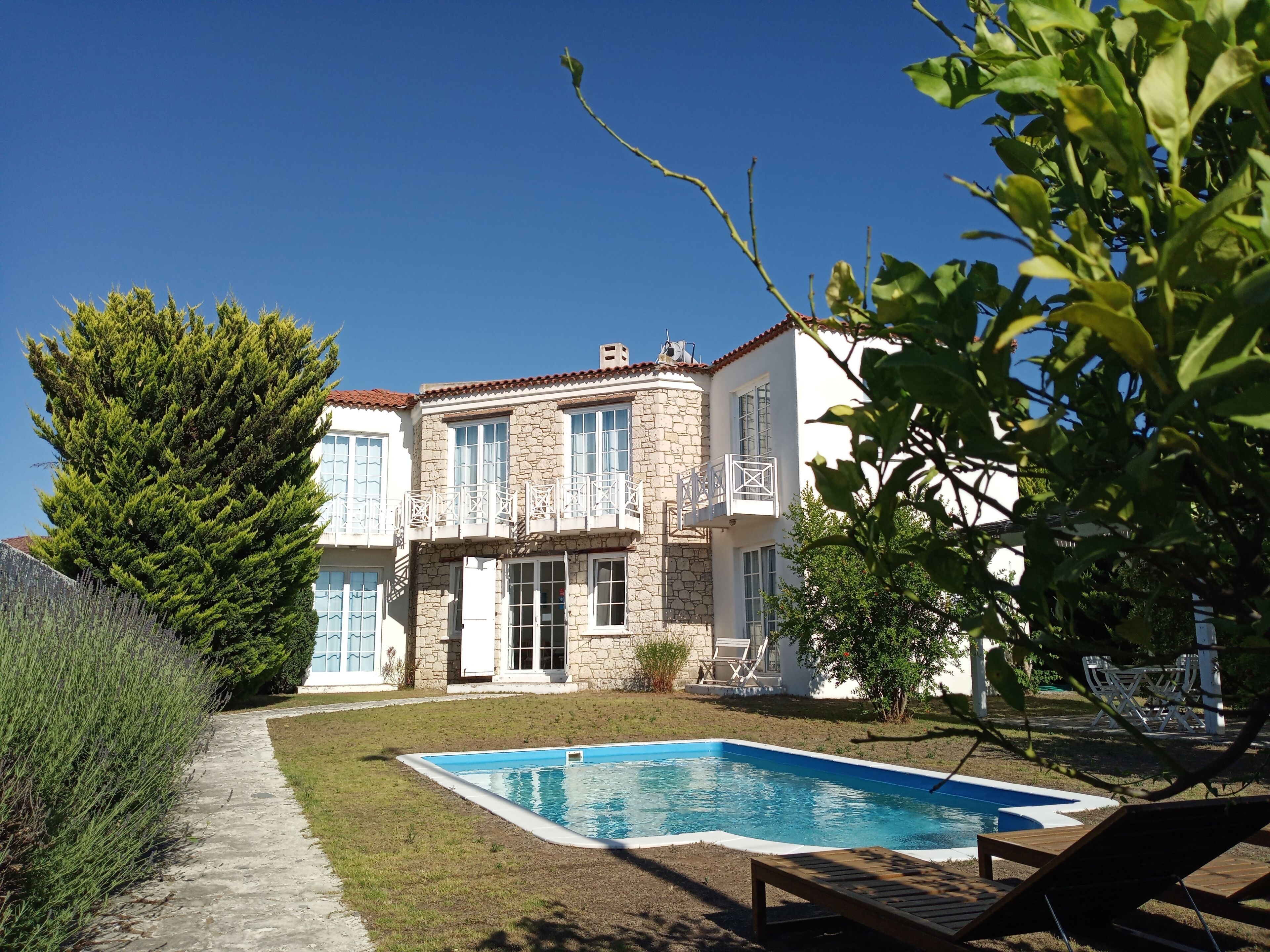 Ein zweistöckiges Haus mit Swimmingpool, Steinverkleidung und einem Garten.