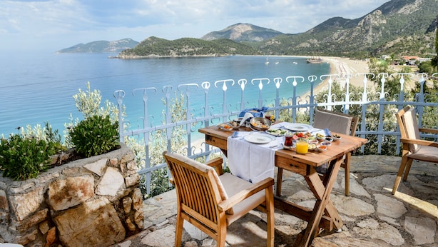 Mesa posta para o café da manhã, com vista para o mar e montanhas.