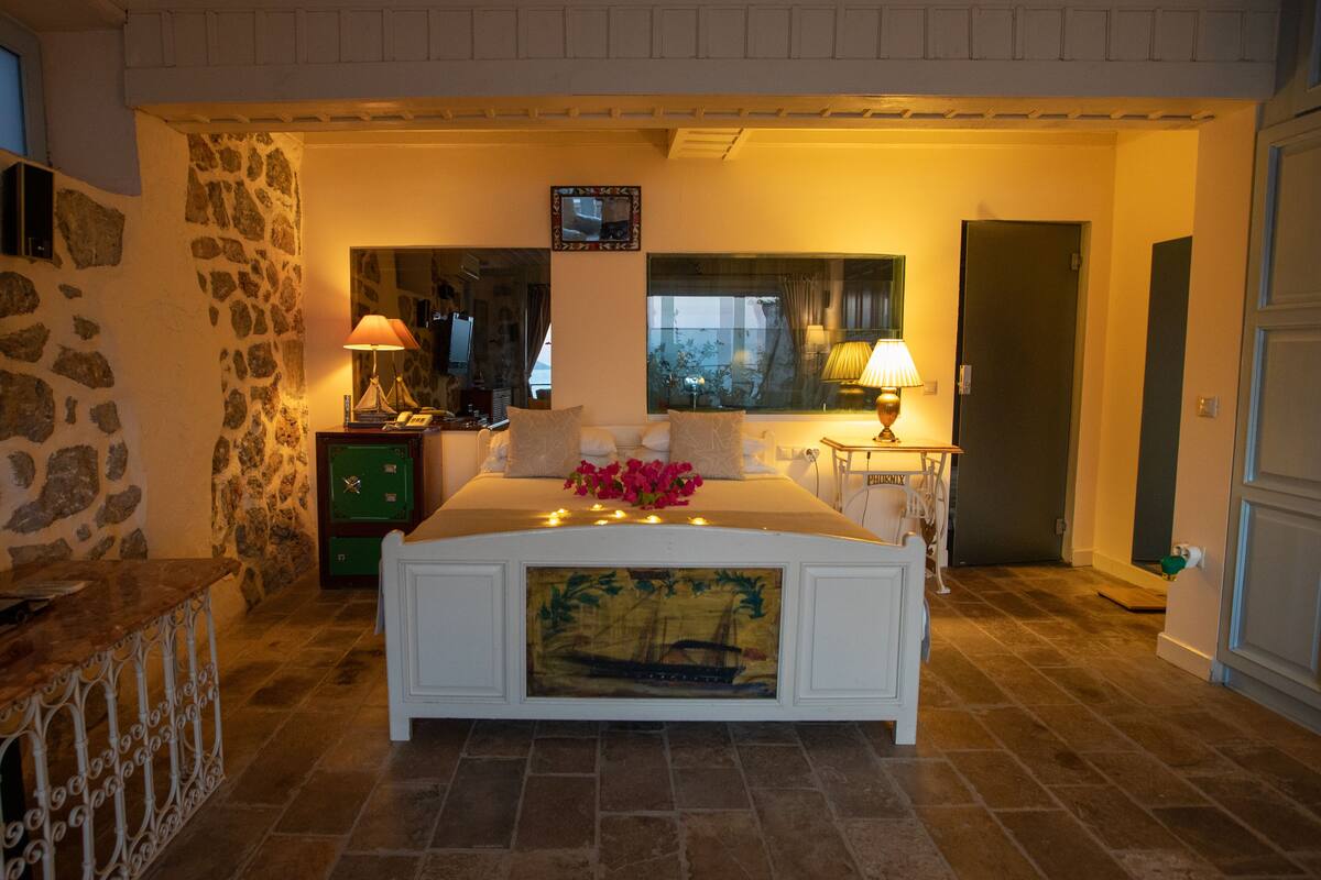 Un dormitorio con una cama grande, pared de piedra y una ventana con cortinas.