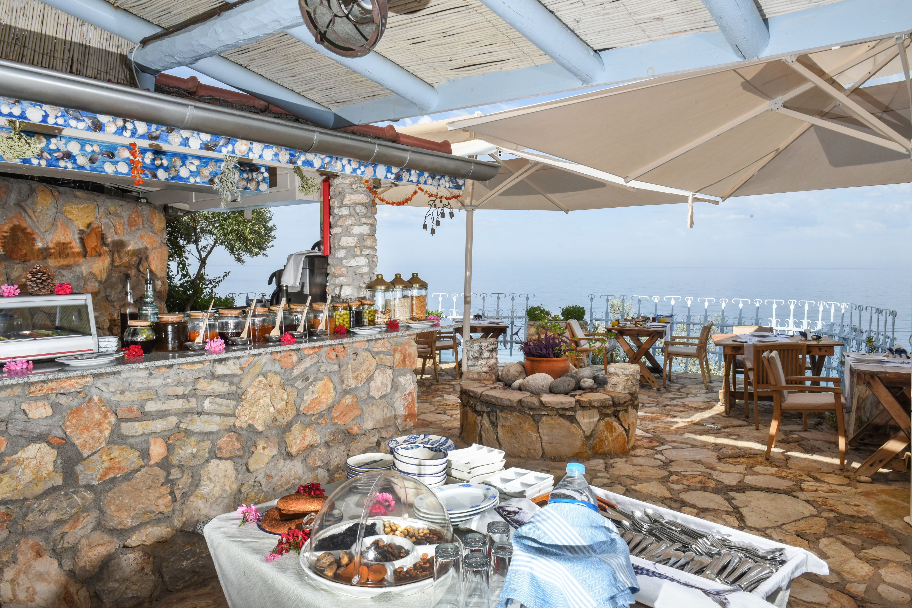 An outdoor dining area with stone walls, a variety of dishes, and a scenic view.