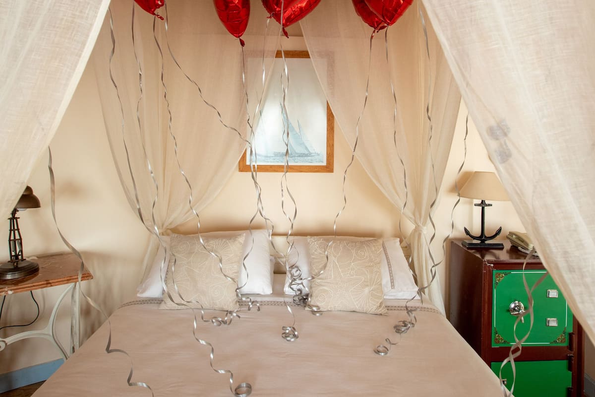 Una cama con dosel, globos con forma de corazón rojo y luces de adorno.