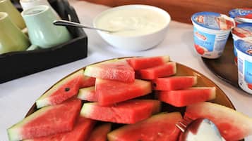 A plate of watermelon slices, a bowl of yogurt, and yogurt cups on a table.