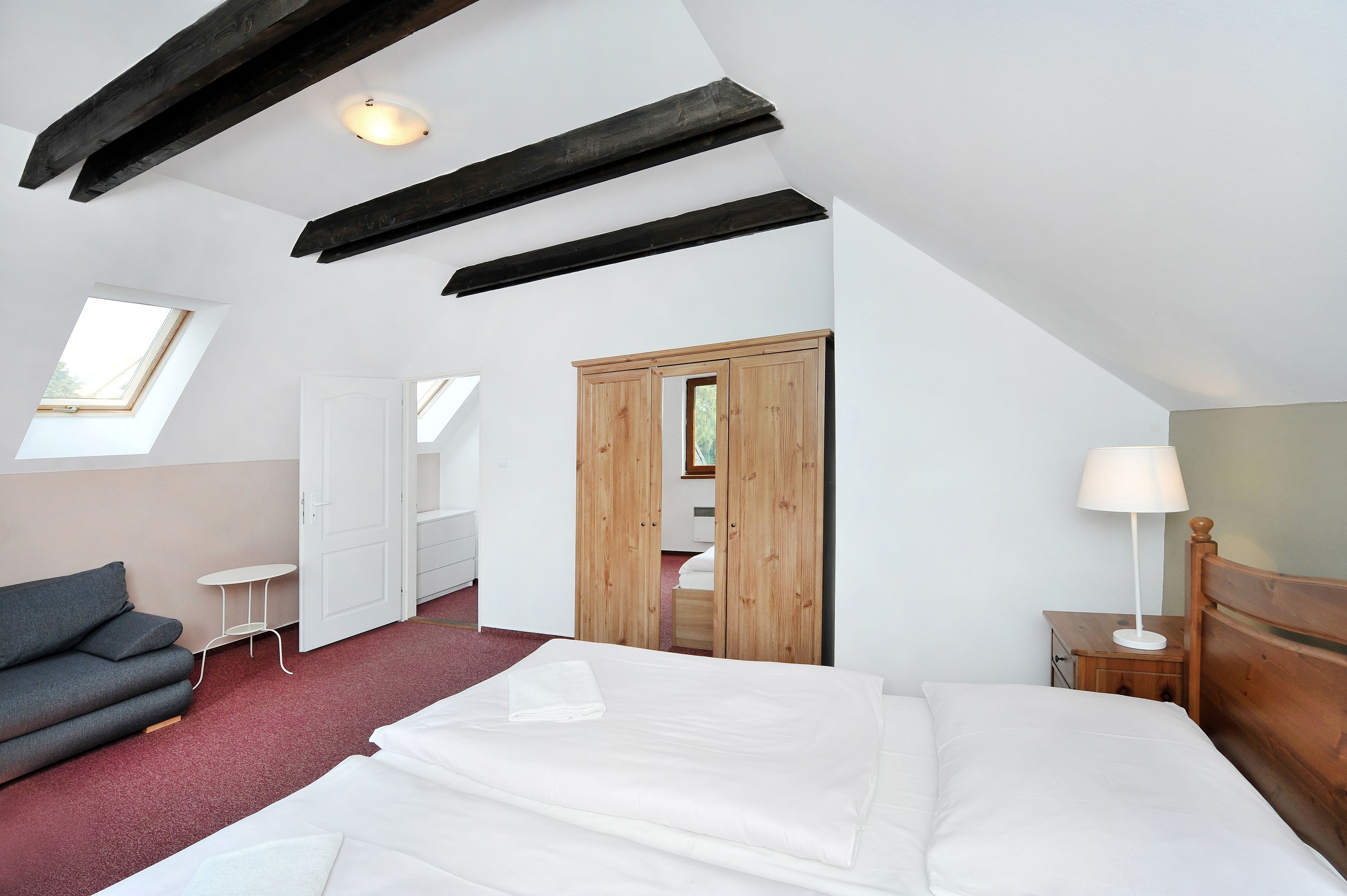 Une chambre à coucher comprenant un lit, un canapé, une petite table, une table de chevet, une lampe et une armoire.