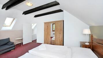 Une chambre à coucher comprenant un lit, un canapé, une petite table, une table de chevet, une lampe et une armoire.