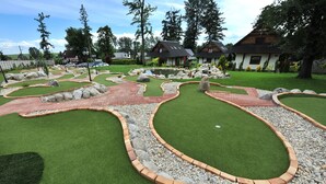 A landscaped garden with artificial grass, stone borders, and a pond. - APLEND Domčeky Tatry Holiday (Velky Slavkov)