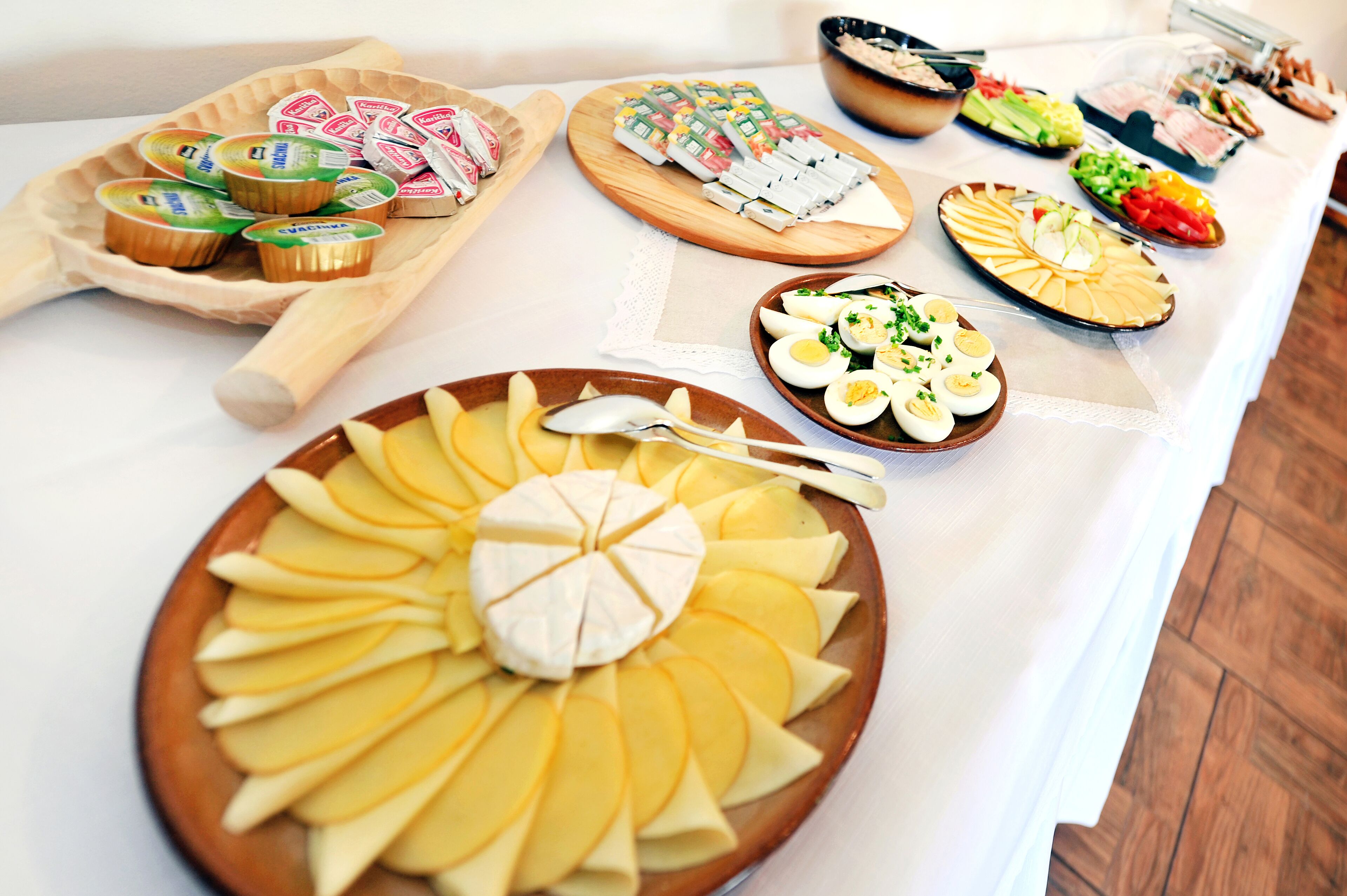 A buffet table with various food items including yogurt, cheese, eggs, and salads.