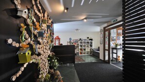 A hallway with a wall decorated with logs and birdhouses, leading to a seating area with a sofa and a small table. - APLEND Domčeky Tatry Holiday (Velky Slavkov)