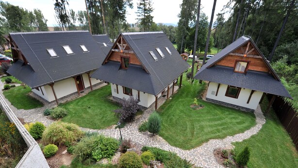 A row of three wooden cabins with sloped roofs, surrounded by well-maintained lawns and a stone pathway. - APLEND Domčeky Tatry Holiday (Velky Slavkov)